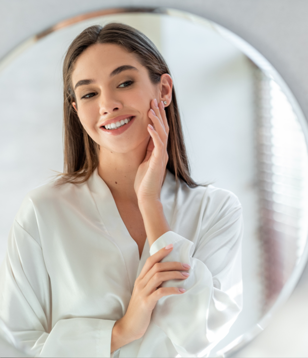 Woman smiling as she looks at herself in the mirror. 