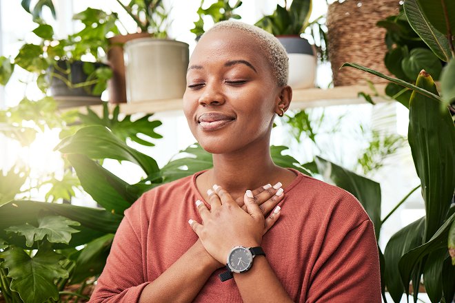 Woman smiling as she relaxes and crosses her hands over her chest. 