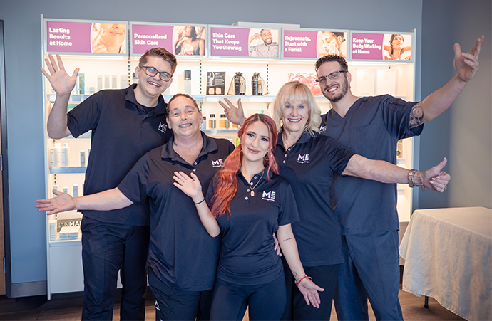 Group of employees at Massage Envy franchised location standing in front of product display. 