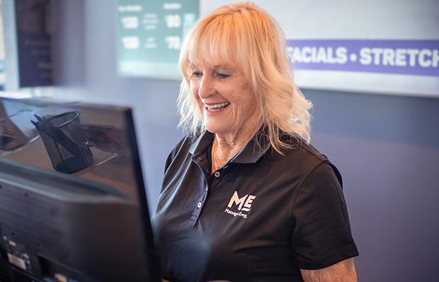 Sales associate at Massage Envy franchised location standing in front of computer. 