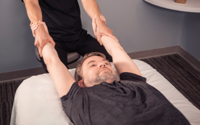 Man lying on table as therapist performs stretch. 