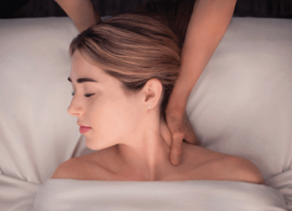 Woman relaxing as therapist massages her neck. 