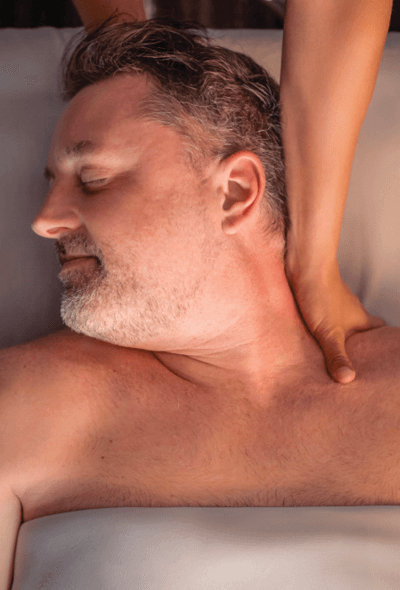 Man with his head turned to the side as a therapist massages his neck. 