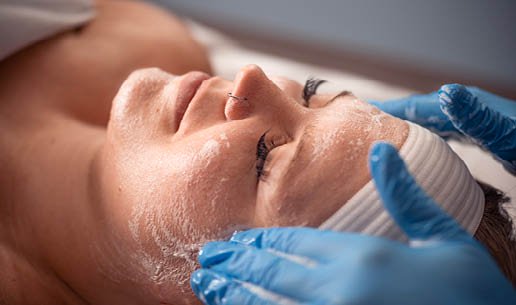 Close-up of esthetician's hands as she performs Clarifying Acne Chemical Peel service. 