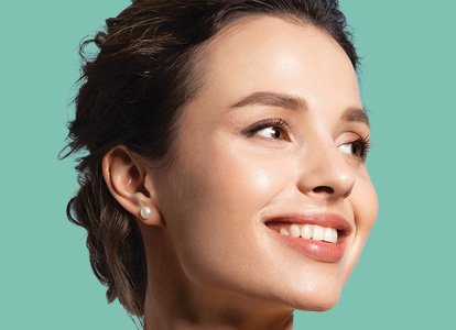 Close-up of woman staring off to the side in front of a light green background. 