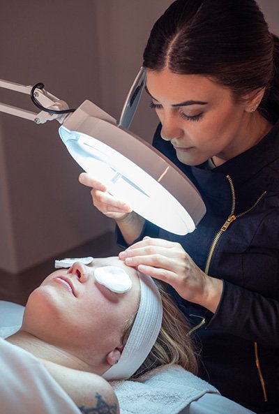 Close-up of esthetician as she looks down during an acne clarifying facial. 