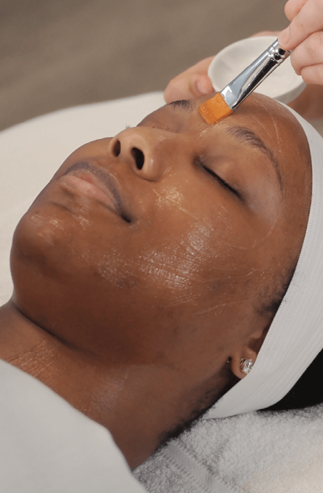 Woman relaxing during her customized facial session at Massage Envy clinic.