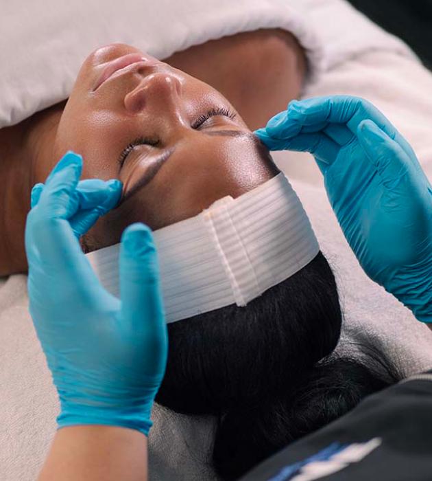 Esthetician massaging client's face during a facial service.