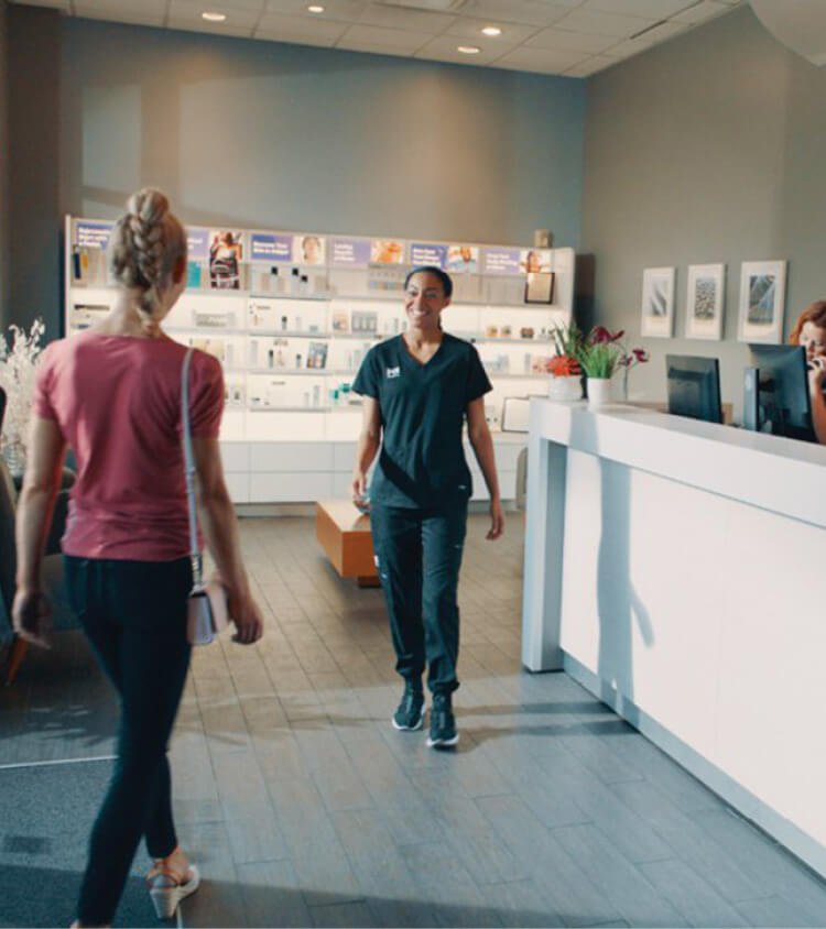 Massage Envy staff member handing tablet to client. 