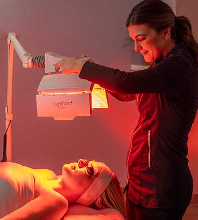 Esthetician standing over client during Nourishing Light Treatment.