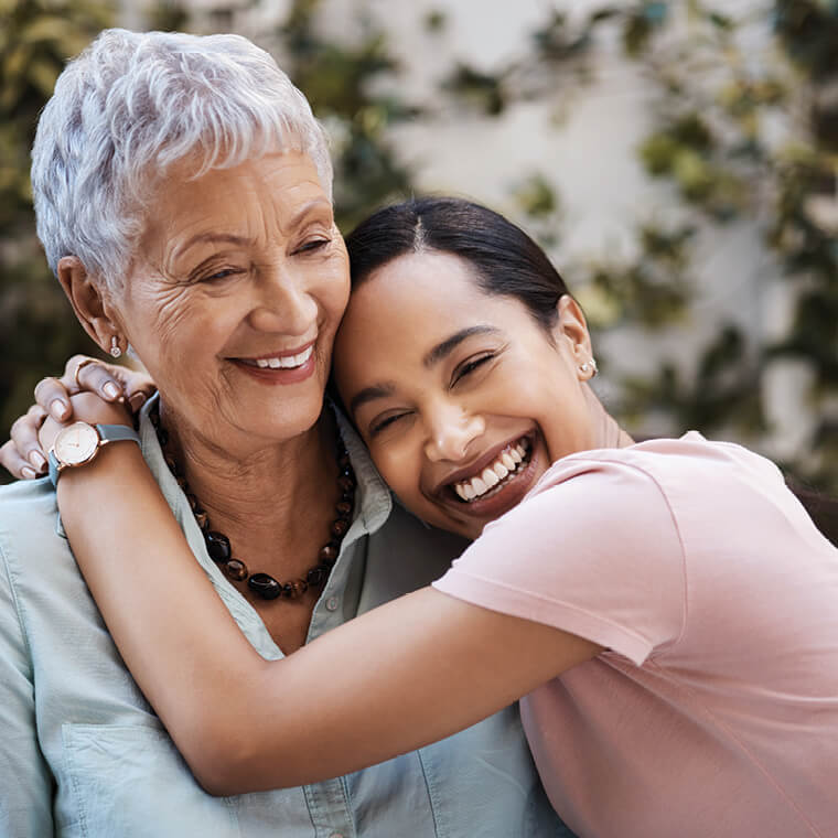Daughter smiling as she embraces her mother. 