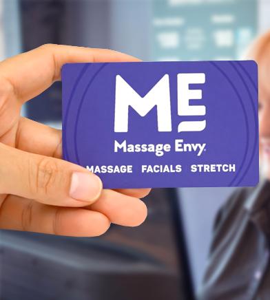 Close-up of a woman's hand holding a Massage Envy gift card. 