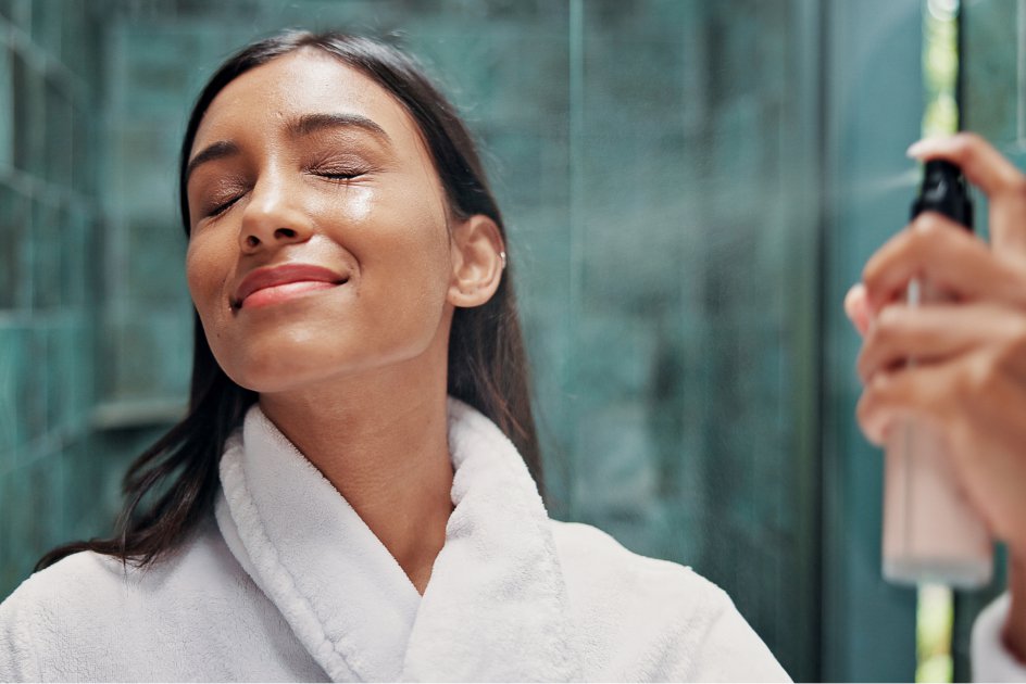 Woman closing her eyes as she sprays herself with skin care product. 